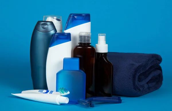 Lozione e schiuma per rasatura, una serie di cosmetici per doccia e un asciugamano su uno sfondo blu — Foto Stock