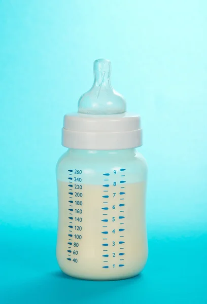 El biberón pequeño para la alimentación del niño, sobre azul —  Fotos de Stock