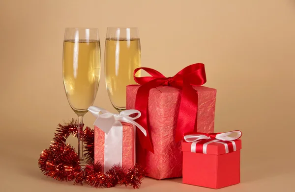 Vakken met Nieuwjaar geschenken, wijn glazen met champagne, klatergoud op een beige achtergrond — Stockfoto