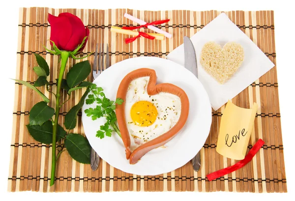 Sausage in the form of heart on a white plate, scrambled eggs and bread, red rose isolated on white — Stock Photo, Image