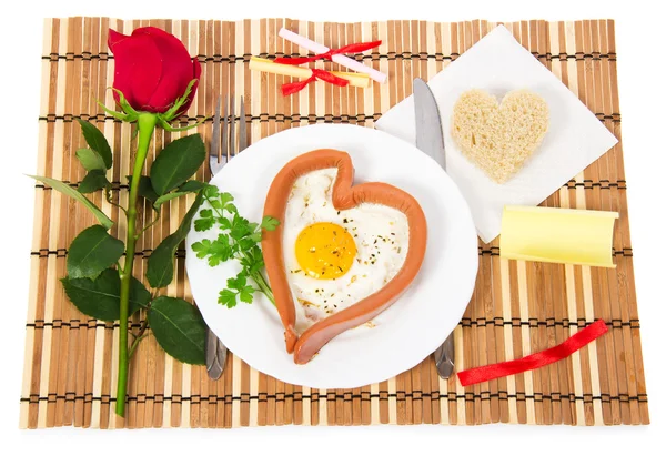 Valentine's Day. Sausage in the form of heart, fried egg, bread, red rose, notes with prediction on a bamboo napkin — Stock Photo, Image
