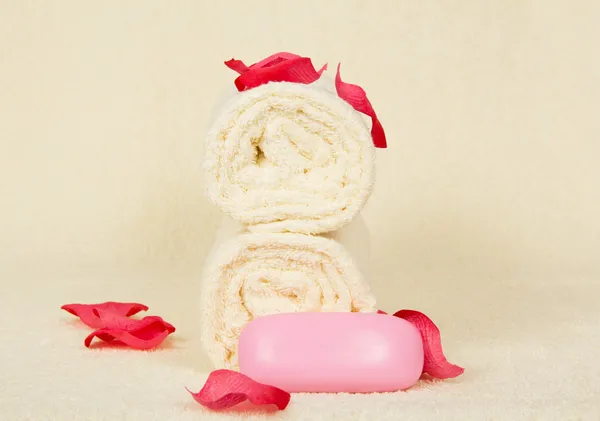 Serviettes un rouleau, le savon, décoré de pétales roses sur un chiffon éponge — Photo