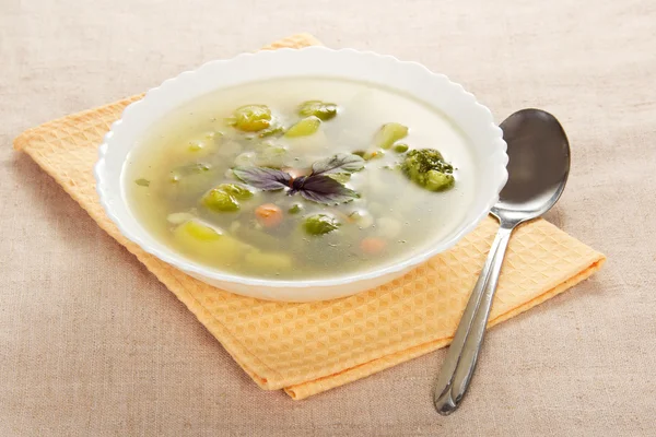 Plaat van plantaardige soep, servet en lepel op een rouwgewaad — Stockfoto