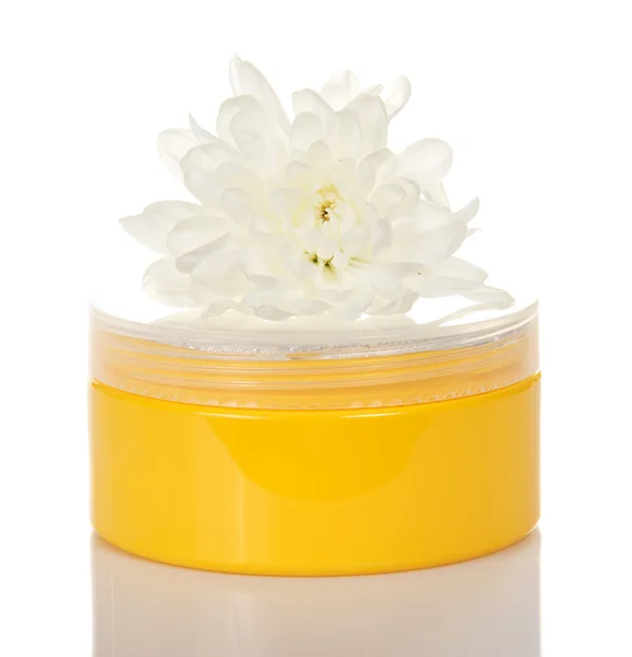 Crema cosmética en el recipiente amarillo y flor aislada en blanco —  Fotos de Stock