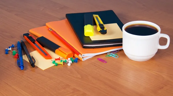 En uppsättning office tillbehör, dagbok, övningsböcker, tom för anteckningar och en kopp kaffe på ett bord — Stockfoto