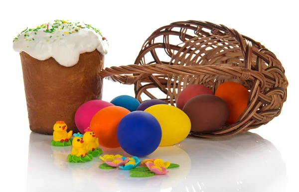 Eggs near a basket and an Easter cake with the sweet jewelry, isolated on the white — Stock Photo, Image