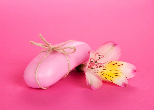 Kwiatek alstroemeria i kawałek mydła na różowym tle — Zdjęcie stockowe