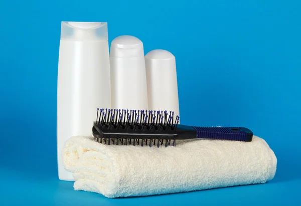 Brosse à cheveux sur une serviette éponge et un ensemble de cosmétiques pour une douche sur un fond bleu — Photo