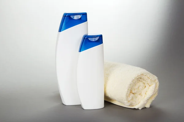 L'asciugamano diminuito, lo shampoo e il gel sul grigio — Foto Stock