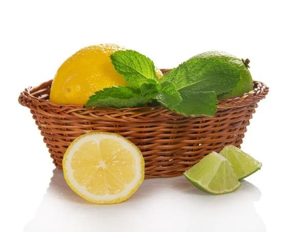 Citron, citron vert et menthe dans un panier, tranches de fruits près d'un panier, isolé sur blanc — Photo