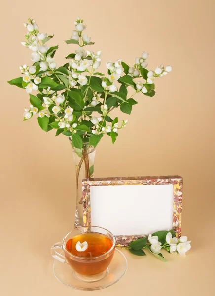 Cup of tea, motley frame and jasmine bouquet — Stock Photo, Image