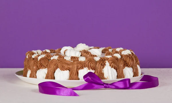Beyaz bir bez ve mor zemin üzerine bir şerit bisküvi pasta — Stok fotoğraf