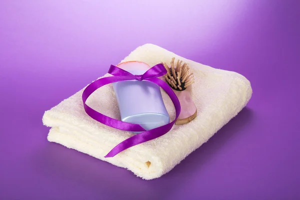 Towel, hairbrush and the shampoo, decorated with a ribbon on the violet — Stock Photo, Image