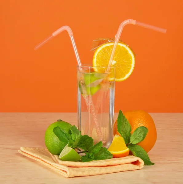 Szklankę napoju ze słomy, ozdobiony jest parasol i pomarańczowy segmentu, cytrusy i serwetki na stół — Zdjęcie stockowe