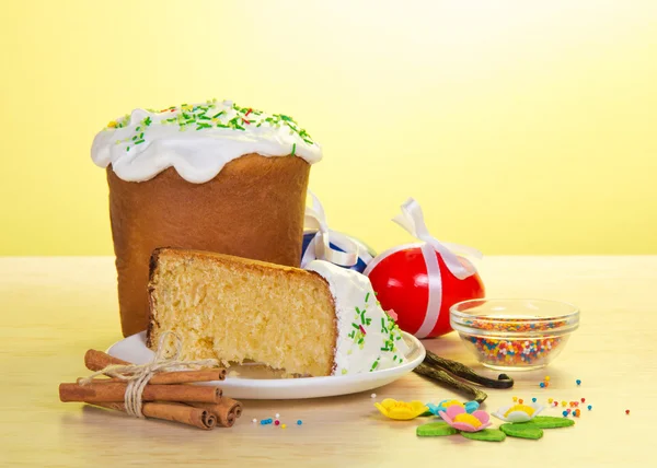 Deel van een Pasen taart op een schotel, eieren, marsepein op een tafel, op een gele achtergrond — Stockfoto
