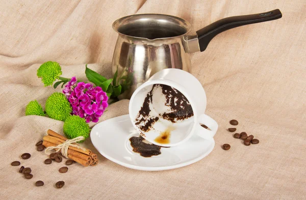 Caffè grosso in una tazza, il turco, il grano di caffè, la cannella e i fiori su un sacco — Foto Stock