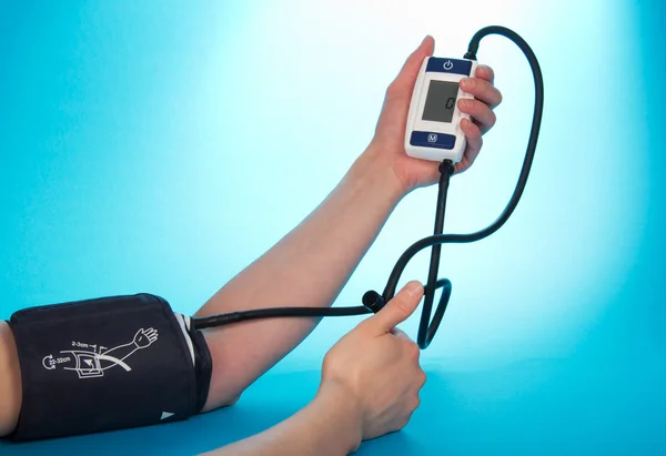 The person supervising a blood pressure by a tonometer, on a blue background — Stock Photo, Image