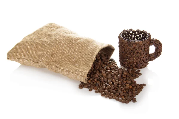 Кофе зерна, которые выпали из мешка, чашка — стоковое фото