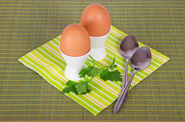 Striped napkin, boiled egg and spoon on a green background — Stock Photo, Image