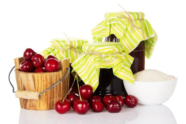 Jars of jam, cup with sugar, a wooden bucket with sweet cherries — Stock Photo, Image