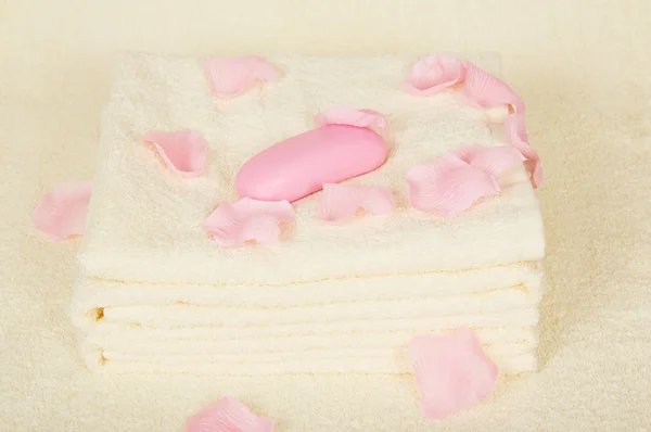 Toallas y jabón bajo pétalos de rosas sobre un paño de rizo —  Fotos de Stock