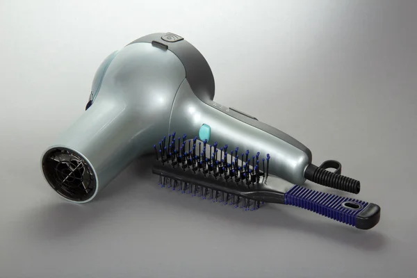 The hair dryer for hair and a hairbrush on a gray background — Stock Photo, Image