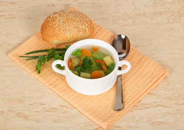 Soup in a bowl, a spoon, bread and greens on a napkin — Stock Photo, Image