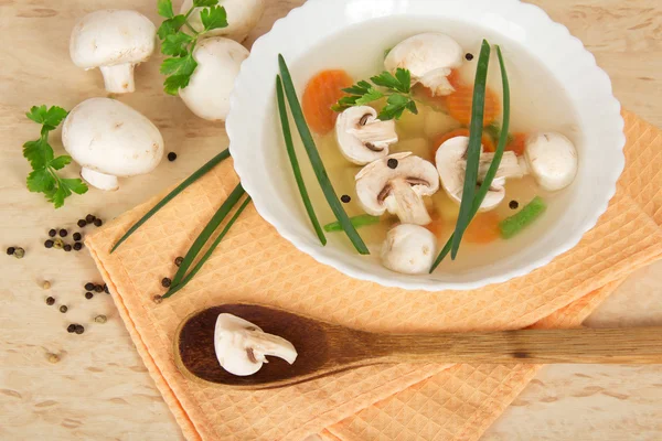 Teller mit Suppe, einem Kochlöffel, Feldpilzen, Petersilie und Gewürzen auf beigem Hintergrund — Stockfoto