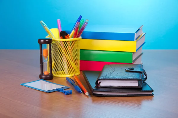 Organizador, bloc de notas, libros, insignia en blanco, bolígrafos en un soporte y relojes de arena en una mesa — Foto de Stock