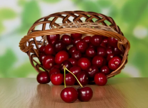 Högen av sötkörsbär som hoppade av en korg, på ett bord — Stockfoto