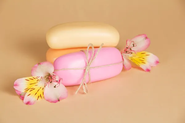 Set of new pieces of soap with a rope and the flower, on a beige background — Stock Photo, Image