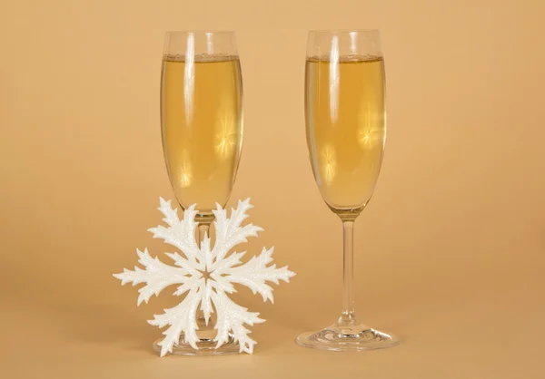 Two festive wine glasses with champagne and a snowflake on a beige background — Stock Photo, Image