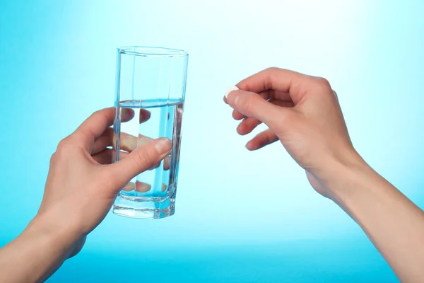 Ruce držící tablet a sklenici s vodou na modrém pozadí — Stock fotografie