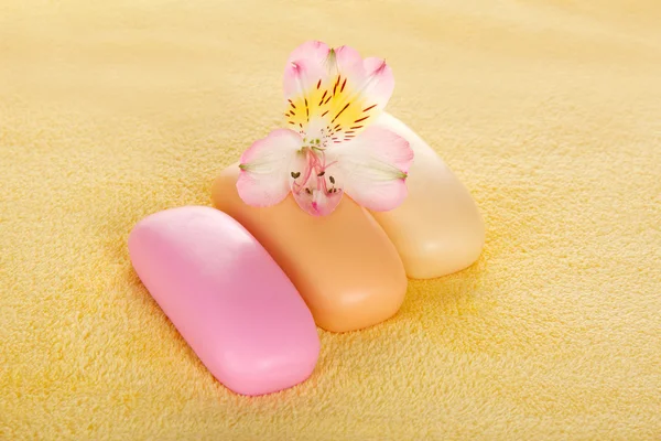 Diversi pezzi di sapone e il fiore su un asciugamano di spugna — Foto Stock