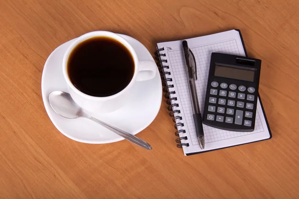 Empty sheets for notes, the handle the calculator and a cup of coffee on a table — Stock Photo, Image