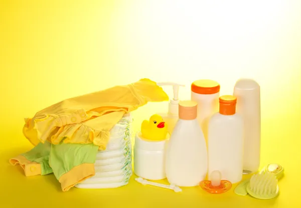 Set for care of the child, clothes and diapers on the yellow — Stock Photo, Image