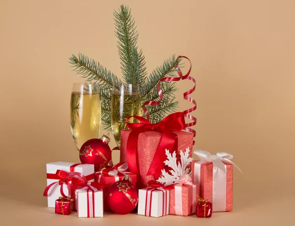 Presentförpackning, leksaker, julgran, serpentin, snöflinga och vinglas med champagne på beige bakgrund — Stockfoto