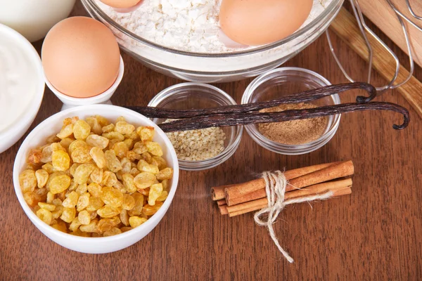 レーズン、ゴマ、シナモンとバニラのさやの棒、小麦粉と卵をテーブルの上 — ストック写真