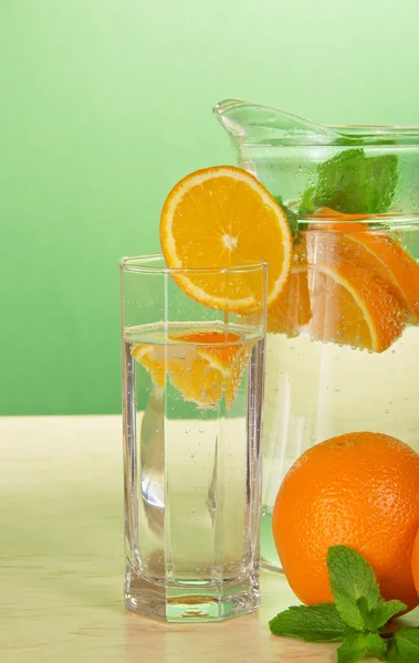 Pić szkła z plasterkiem pomarańczy i dzbanek na stole — Zdjęcie stockowe
