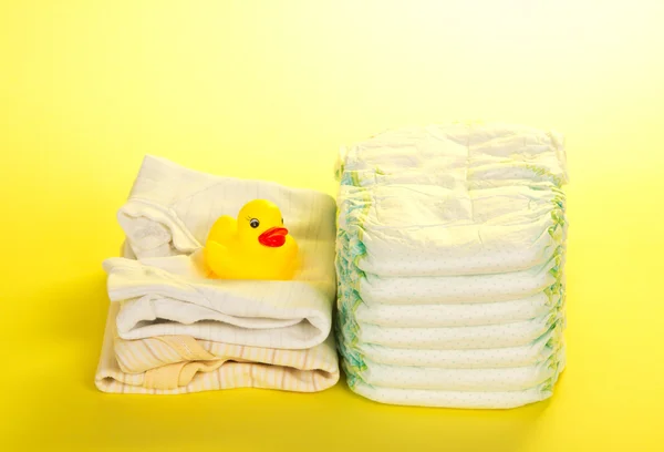 Disposable diapers, clothes and a rubber duckling, on the yellow — Stock Photo, Image