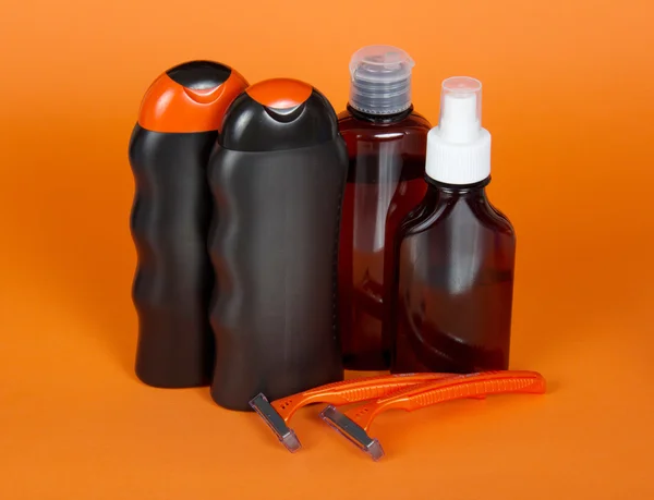 Shampoo, gel, lotion en scheermes op een oranje achtergrond — Stockfoto