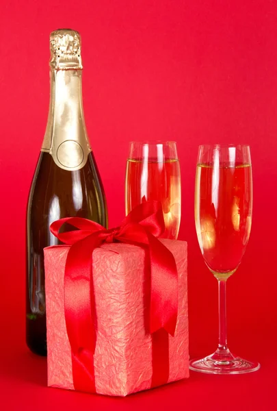 Caja de regalo con cinta y lazo, botella de champán y copas de vino —  Fotos de Stock