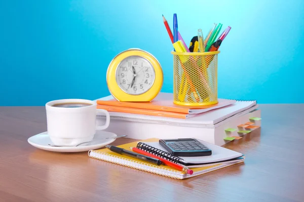 Le livre, un ensemble pour la lettre, un réveil la calculatrice une tasse de café une soucoupe et une cuillère sur une table — Photo