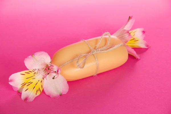 Beautiful flower of an alstroemeria and piece of the soap on a pink background — ストック写真