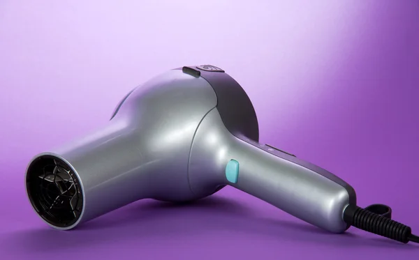 O secador de cabelo em um fundo violeta — Fotografia de Stock