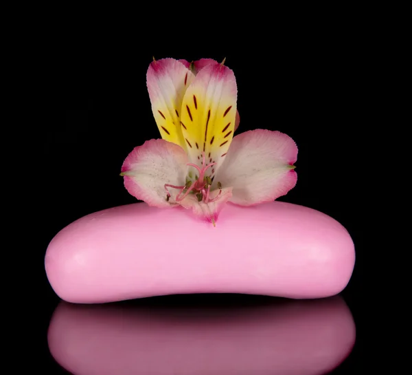 Beautiful flower of an alstroemeria and piece of the soap, isolated on black — Stock Photo, Image