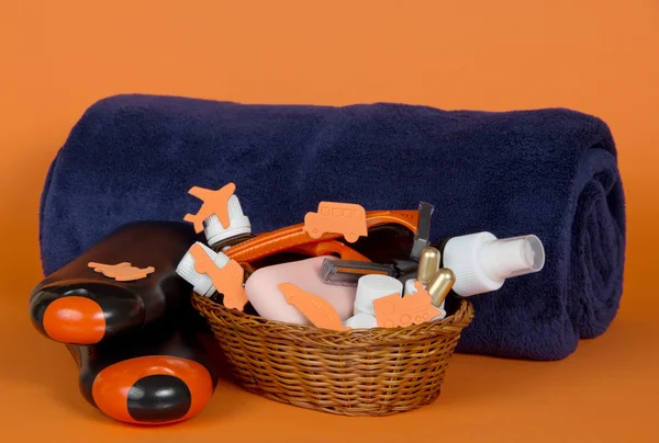 Шампунь, гель, косметика в корзине и большое полотенце на оранжевом фоне — стоковое фото