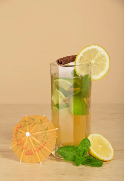 Drink with a lemon slice, a stick of cinnamon and mint on a beige background — Stock Photo, Image