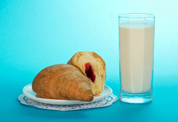 Glas met melk en croissants op een blauwe achtergrond — Stockfoto