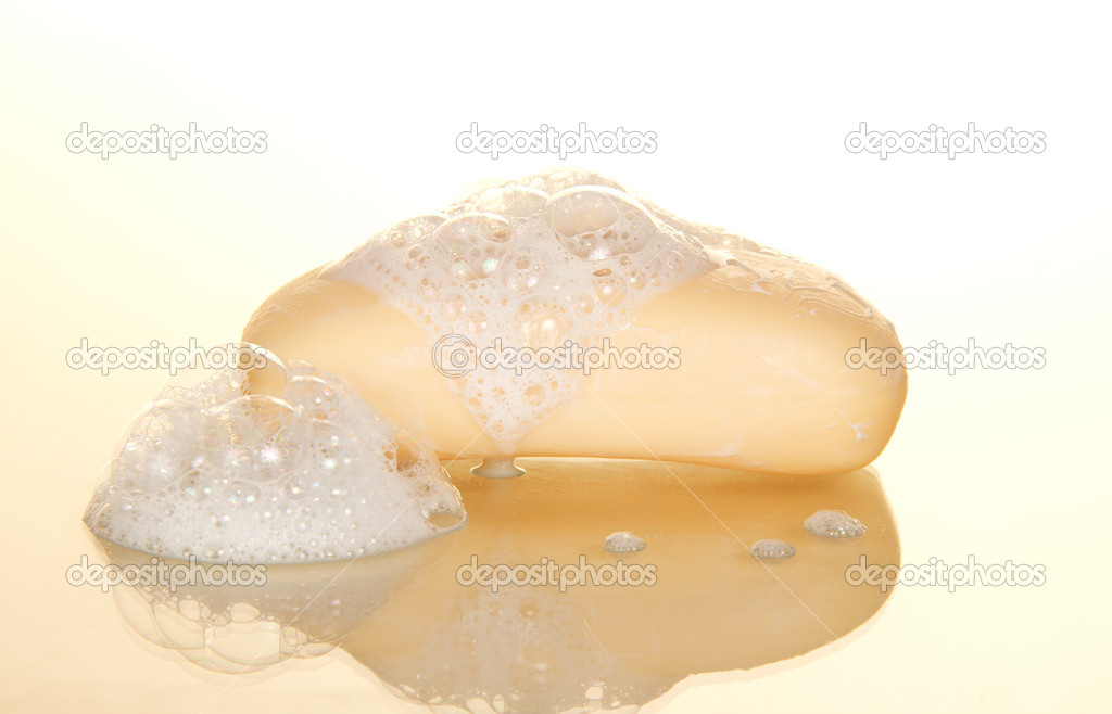 Wet soap with foam on a beige background